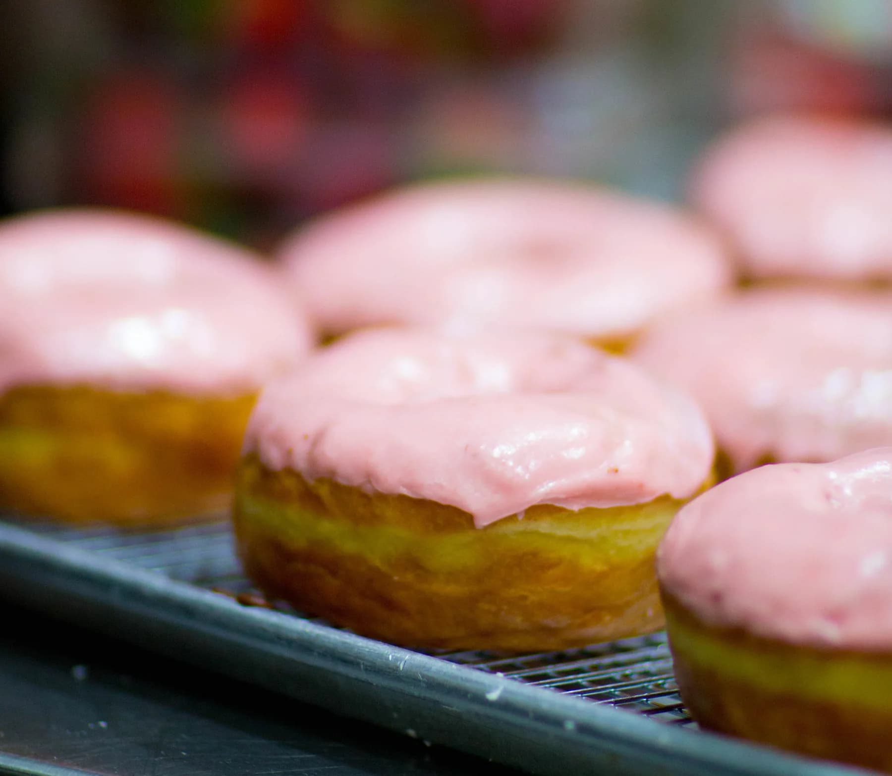 Pink glazed Johnny Doughnuts on a bakery display.